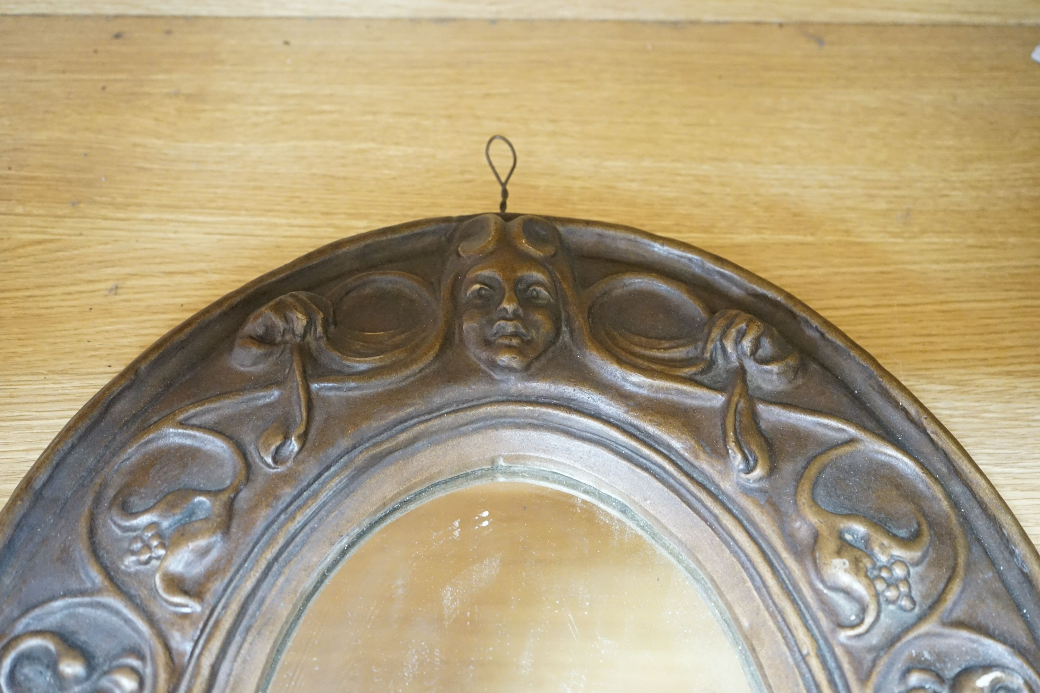 An Art Nouveau style moulded gesso oval mirror, 57cms high